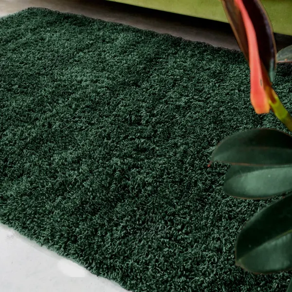 A thick Eden green shaggy rug on a concrete floor.