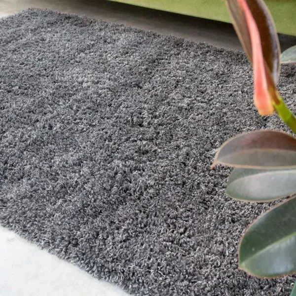 A thick charcoal grey shaggy rug on a concrete floor.