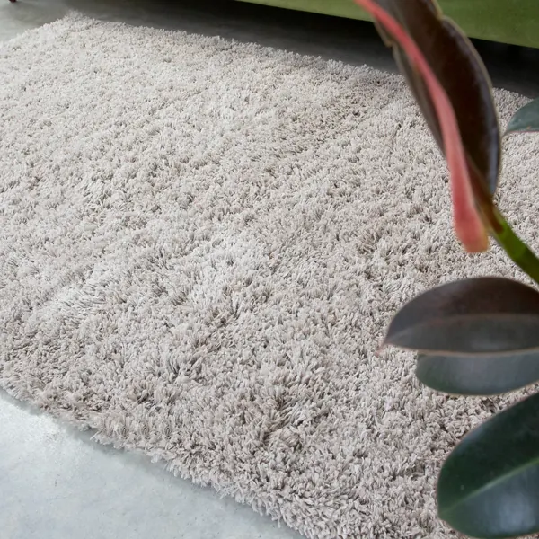 A thick cream shaggy rug on a concrete floor.