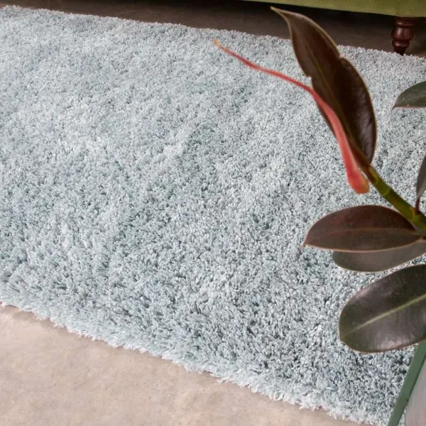 A thick light blue shaggy rug on a concrete floor.
