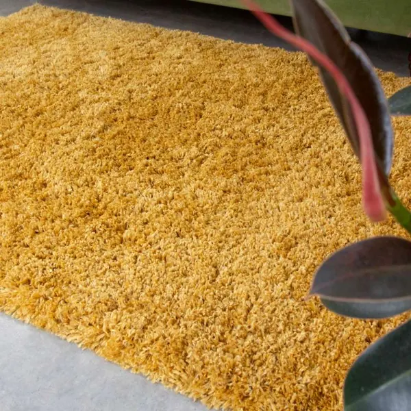 A thick mustard yellow shaggy rug on a concrete floor.