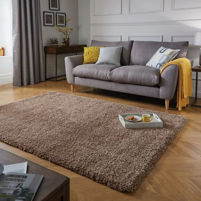 Taupe shaggy rug in a living room with a grey sofa