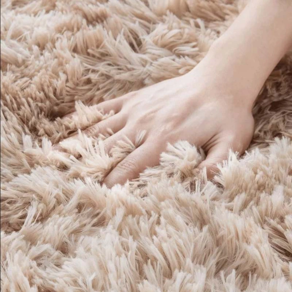 Close-up of hand touching thick shaggy rug fibers.